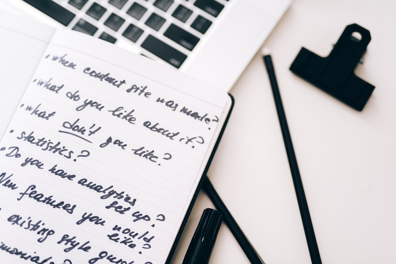 A close-up view of a notebook with handwritten notes alongside a laptop for planning and strategy.