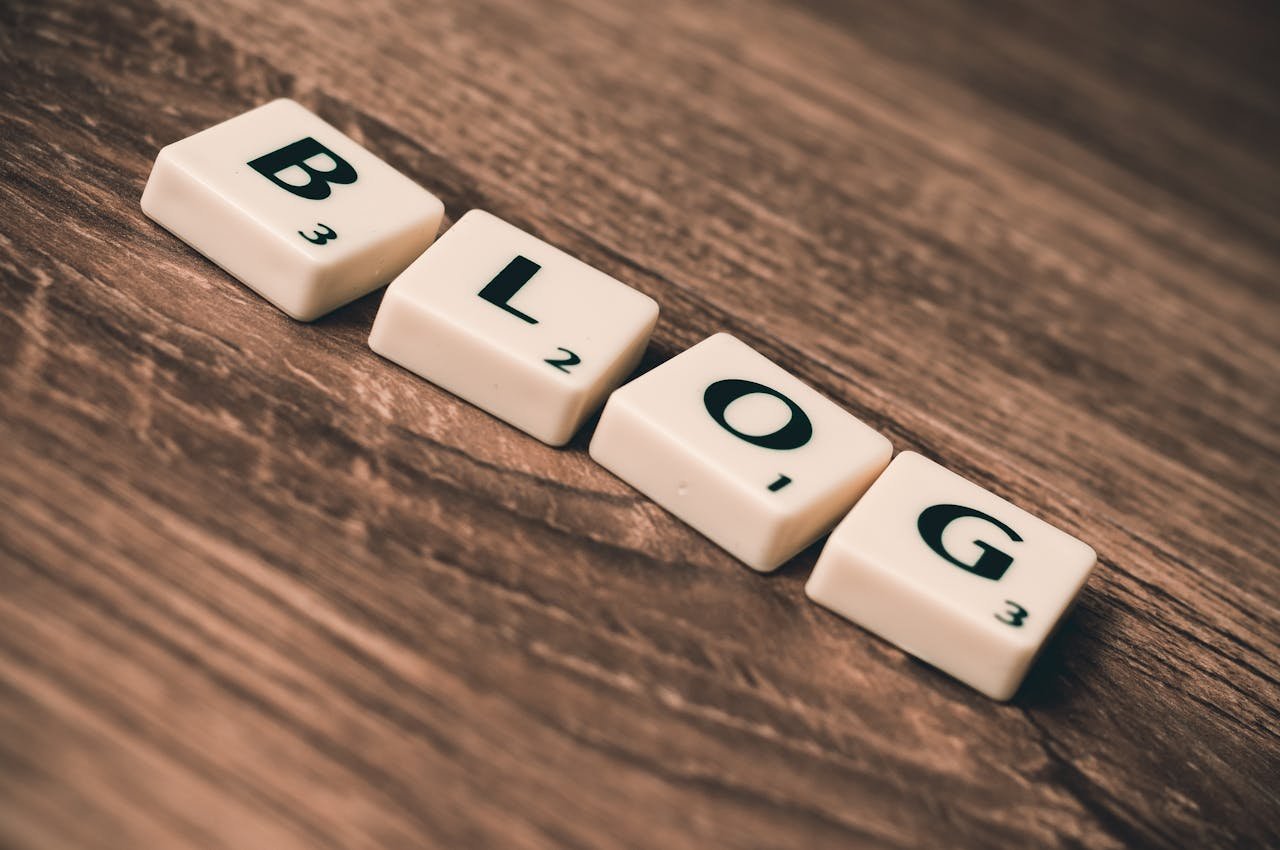 Scrabble tiles spelling BLOG on a wooden background, symbolizing creativity and writing.