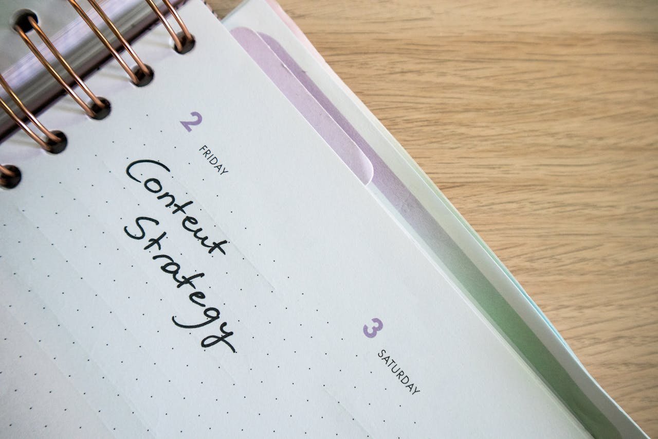 Top view of a notebook open to a day planner featuring Content Strategy handwritten, lying on a wooden desk.